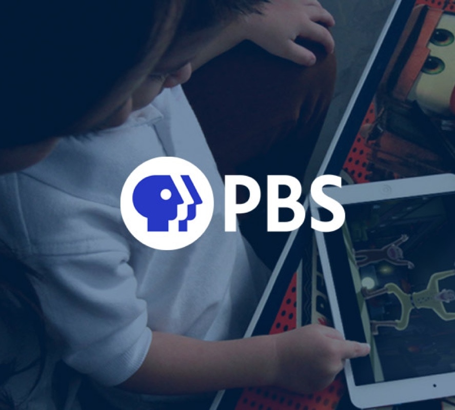 Toddler with a tablet in his hands playing with an educational application and the PBS logo