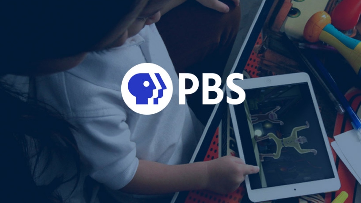 Toddler with a tablet in his hands playing with an educational application and the BBS logo