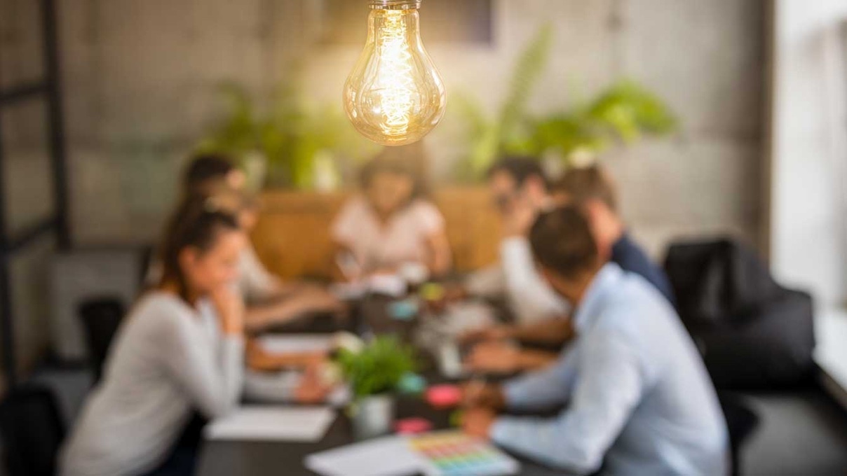 People brainstorming ideas around a table with a light bulb.