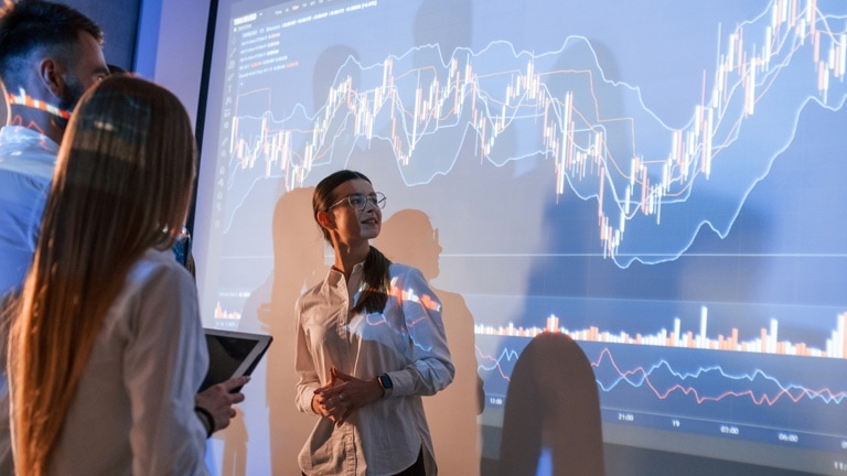 Female leader talking to employees, showing the plan on the projector in office