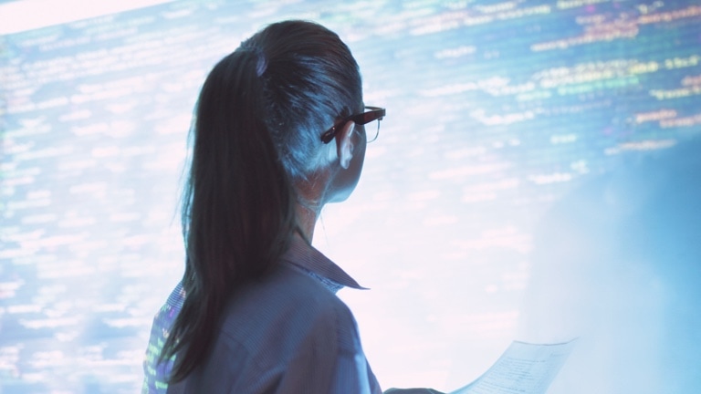 Woman looking at large wall screen with code