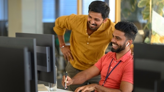 Two young men smiling in front of a computer