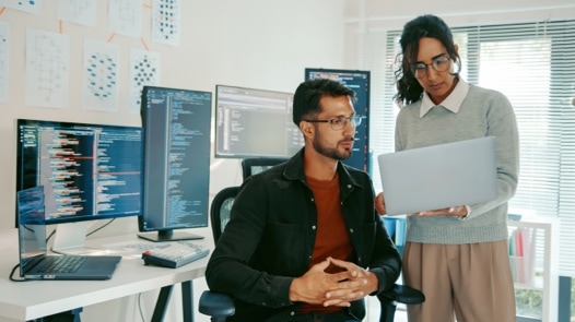 Multi Cultural Programmers Reviewing Code on Laptop in Modern Office