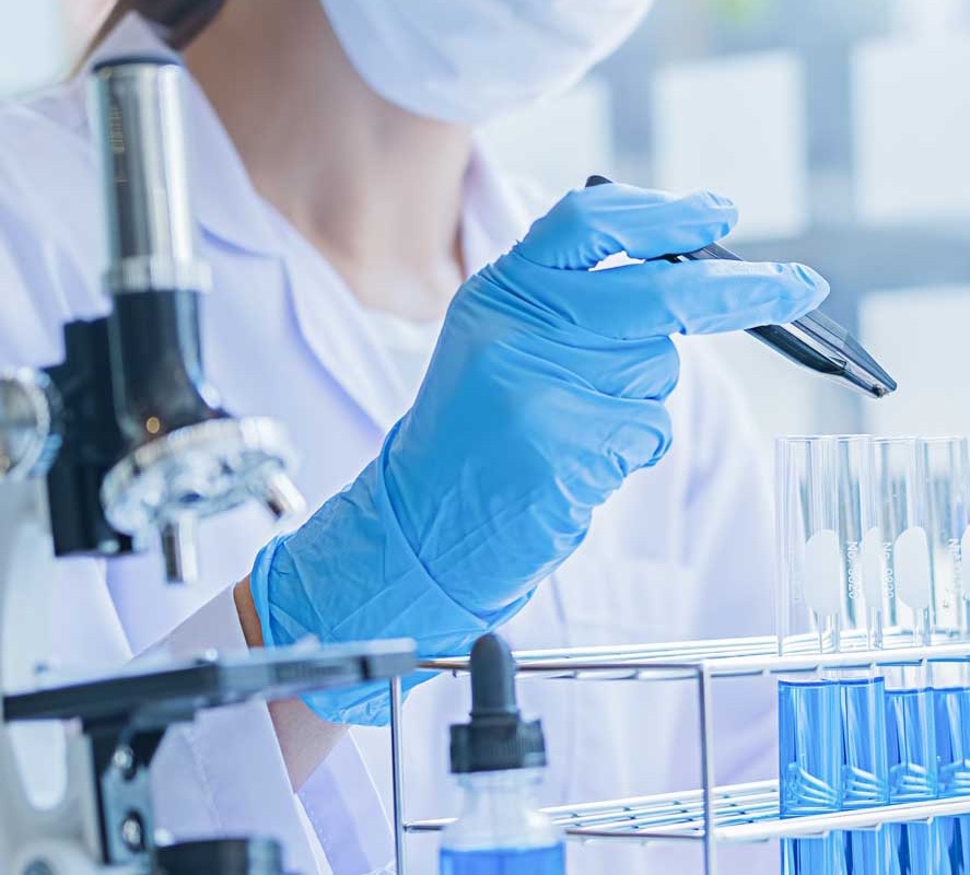 a woman at work in a laboratory with a microscope and test tubes