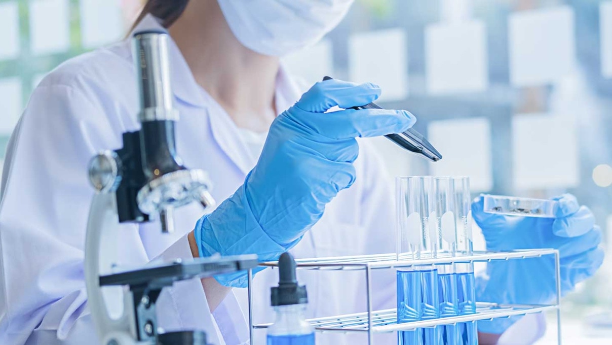 a woman at work in a laboratory with a microscope and test tubes