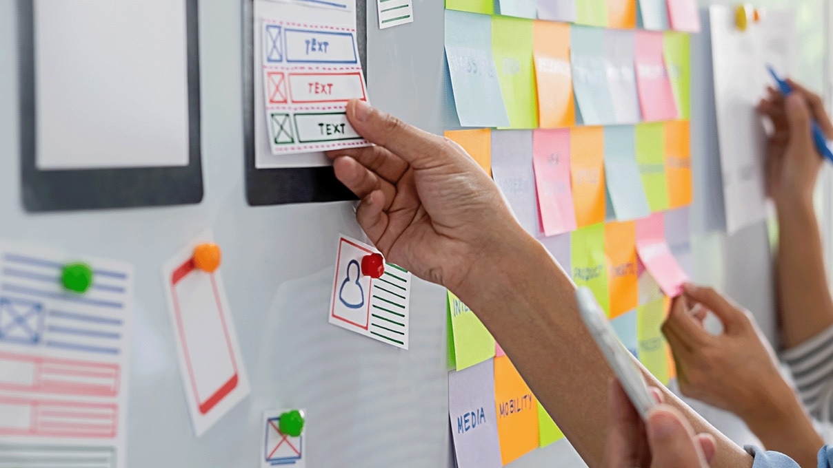 whiteboard with sticky notes and drawings depicting a wireframe work session