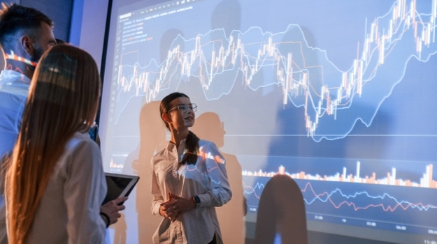 Female leader talking to employees, showing the plan on the projector in office